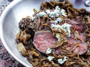 Balsamic glazed oinions over sirloin in a saute pan