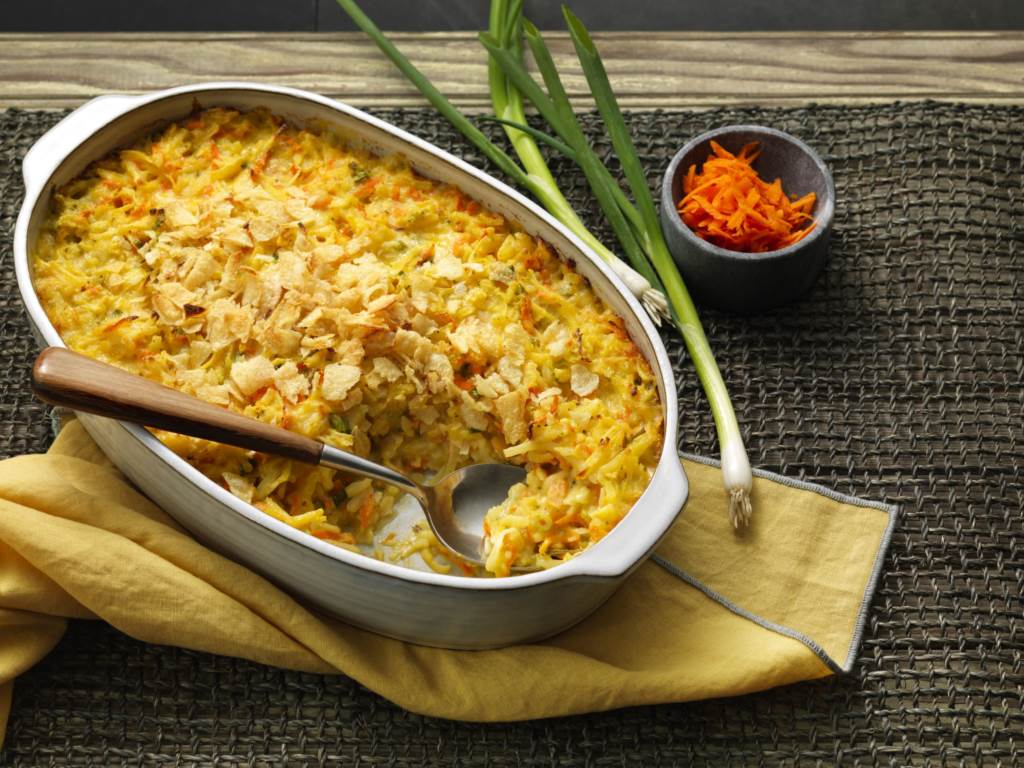 Cheddar Potato Carrot Casserole in pan with spoon for serving